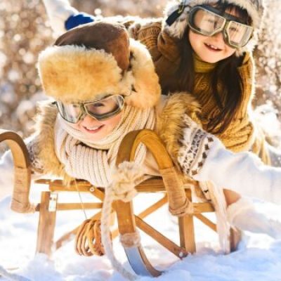 Two,Smiling,Children,Ride,Lying,On,A,Wooden,Retro,Sled